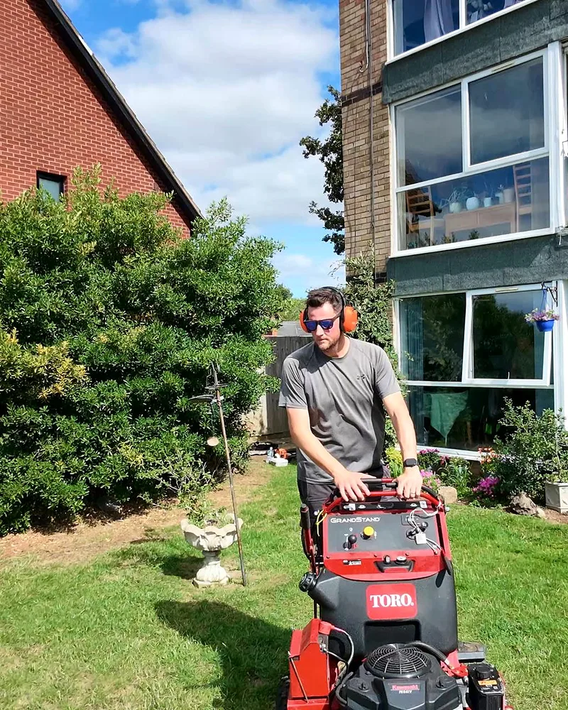 Tom mowing a lawn on a Toro stand-on mower